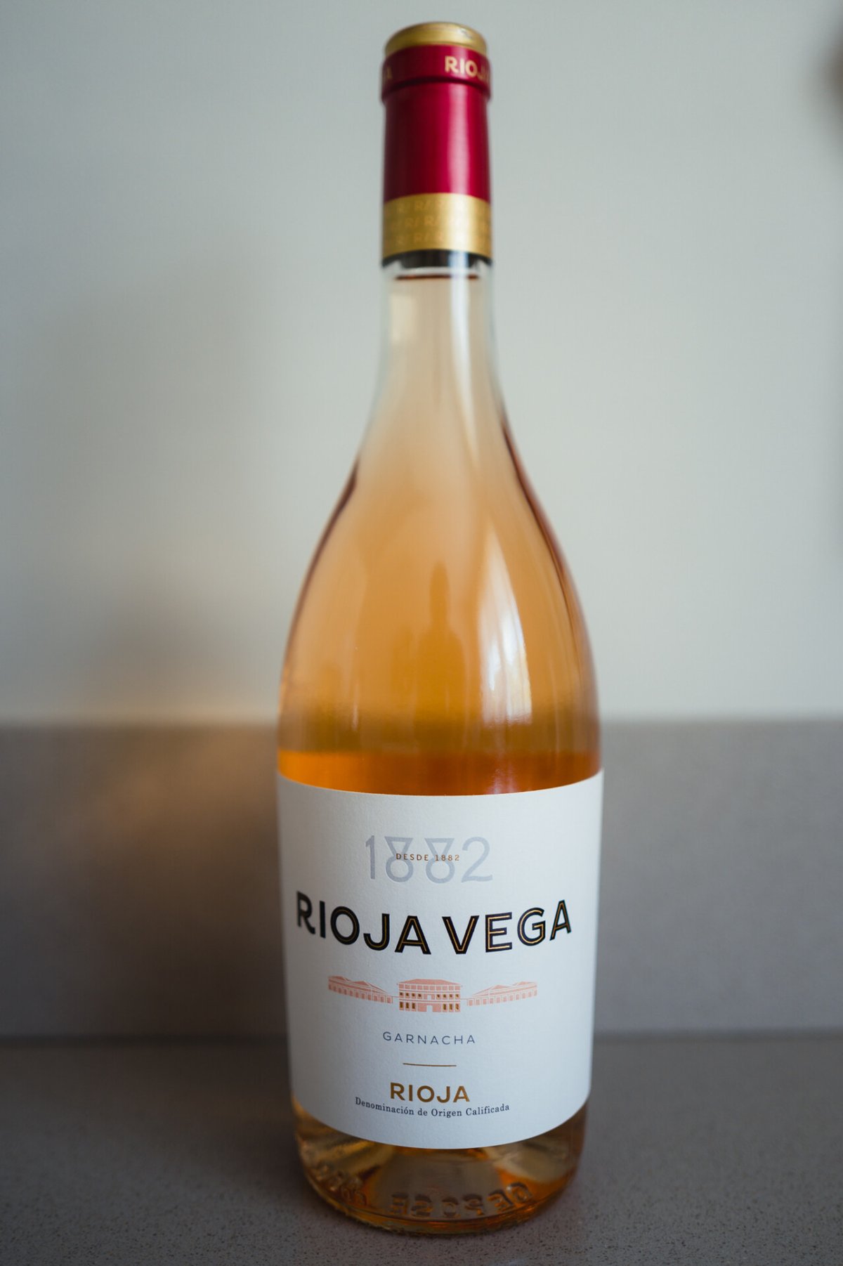 Rioja Vega Garnacha rosé bottle with a salmon-pink wine and red capsule standing alone