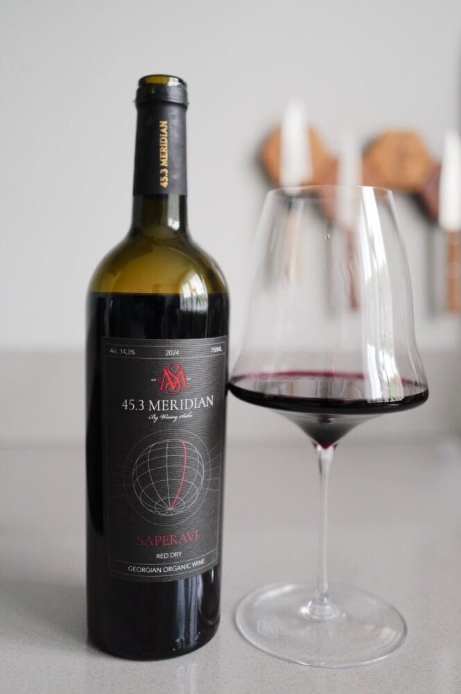 45.3 Meridian Saperavi bottle with a dark label beside a glass of deep red wine