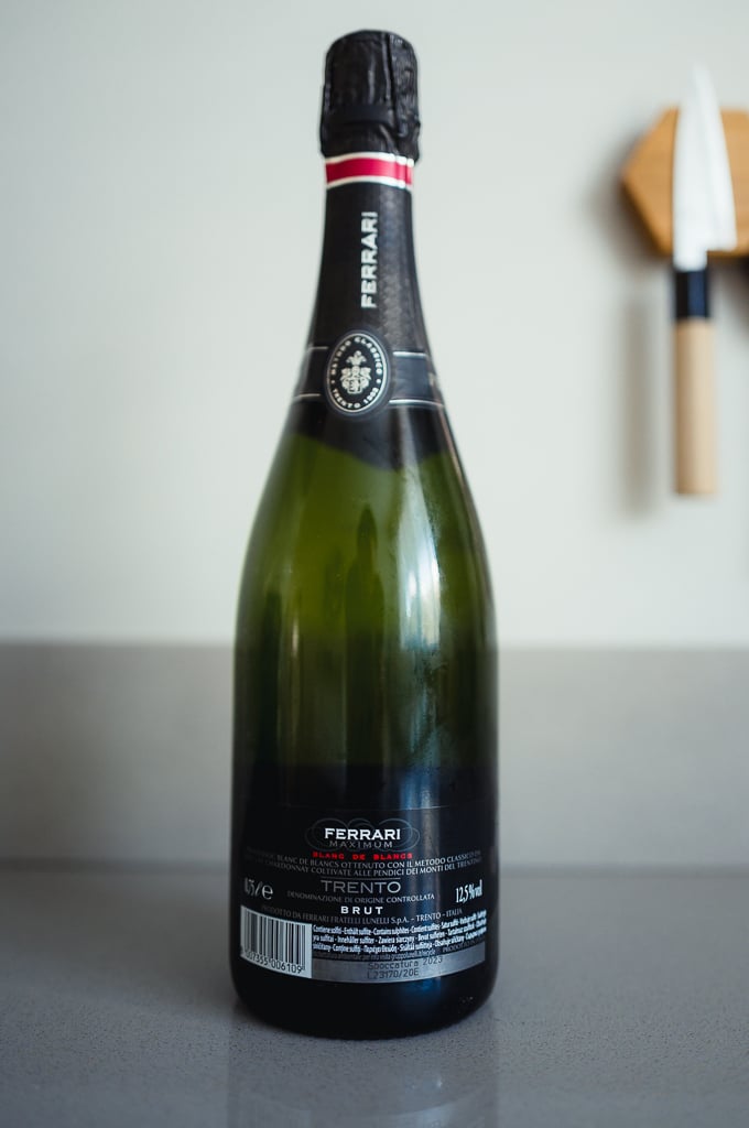 Back label of the Ferrari Maximum Blanc de Blancs Trento Brut bottle standing on a kitchen counter