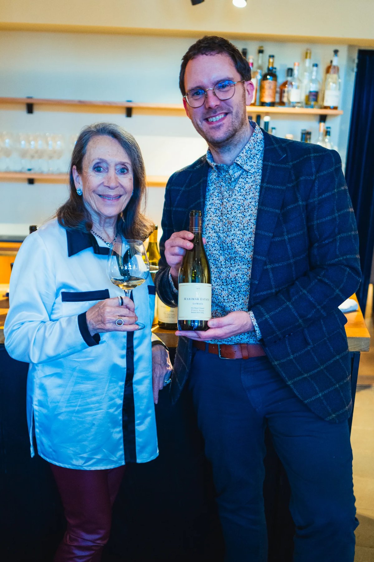 Marimar Torres and Jeroen Vonk smiling, she holds a wine glass and he a Marimar Estate bottle