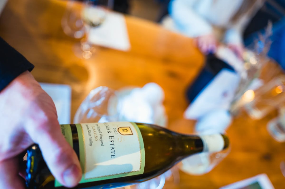 Close-up of a hand holding a Marimar Estate 2020 Albariño bottle at a tasting table