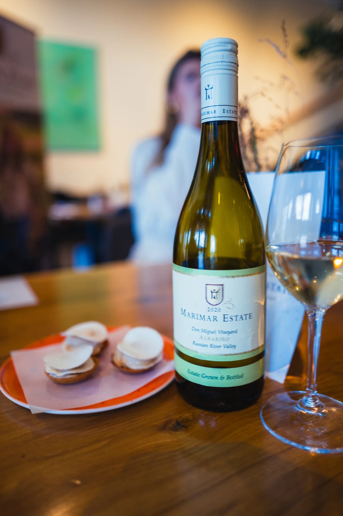 Marimar Estate Albariño bottle on a wooden table with a plate of oysters and a glass of white wine