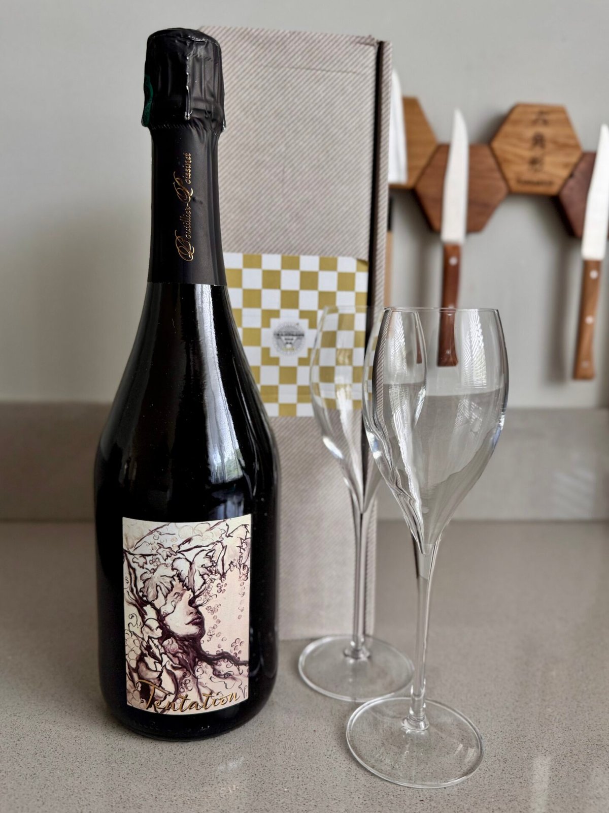 Boutillier-Poissinet Tentation champagne bottle with an illustrated label beside two flutes and a gift box
