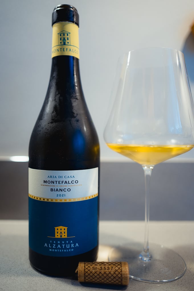 Aria di Casa Montefalco Bianco 2021 bottle beside a glass of golden white wine and a cork