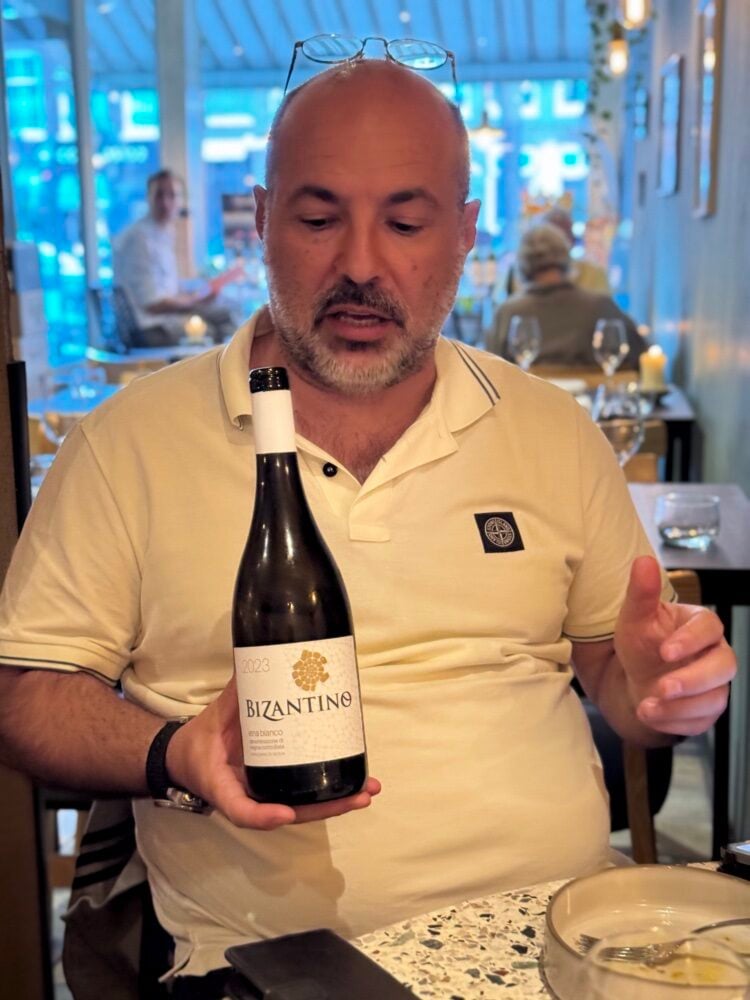 Man in a restaurant presenting a bottle of Bizantino 2023 Etna Bianco