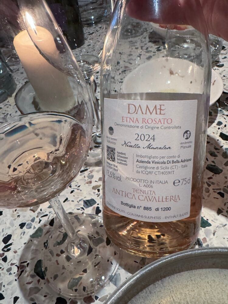 Back label of the Dame Etna Rosato 2024 bottle, bottle number 885 of 1200, beside a glass of rosé