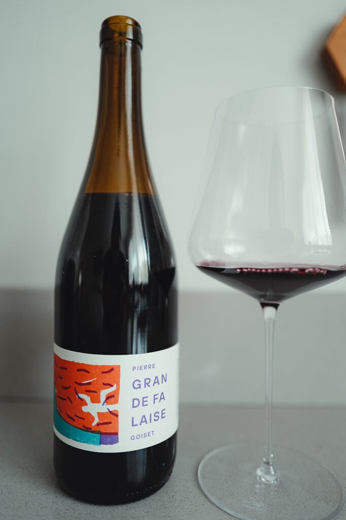 Pierre Goiset Gran de Falaise bottle with an orange label beside a glass of red wine