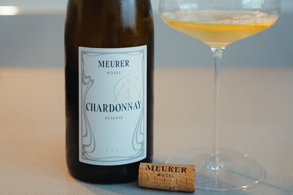 Meurer Mosel Chardonnay Reserve 2021 bottle beside a coupe of golden wine and a branded cork