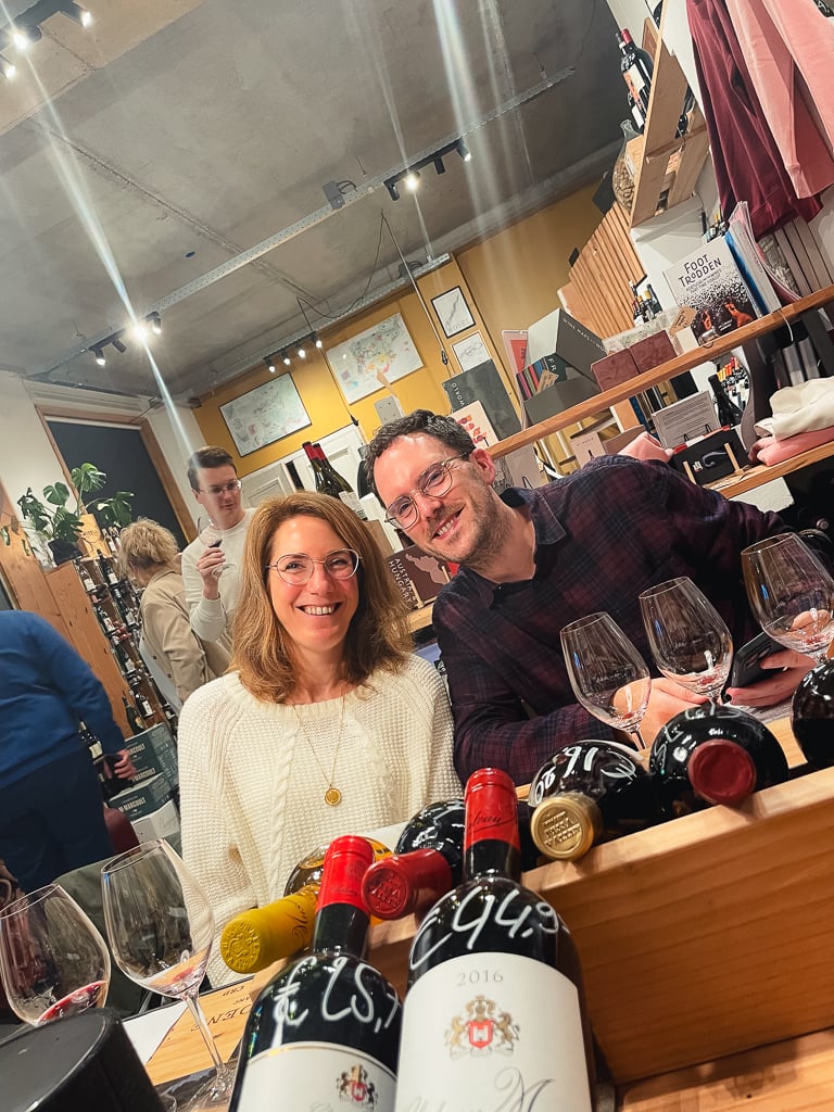 Two smiling guests behind a crate of wine and tasting glasses at Vindict