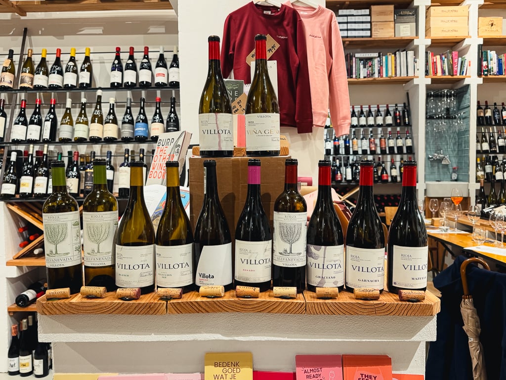 Row of Villota Rioja bottles lined up on a wooden shelf with corks in front