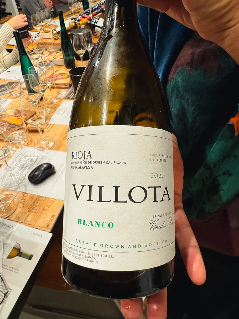 Hand holding a bottle of Villota Rioja Blanco 2020 at the tasting table