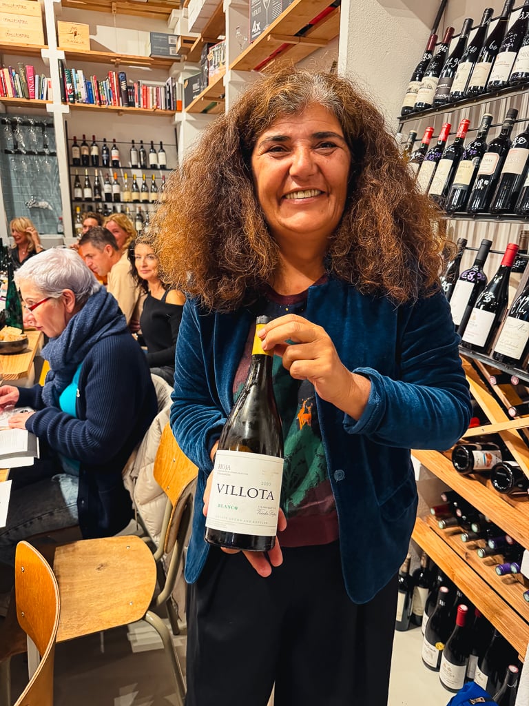 Carmen holding a bottle of Villota Blanco at the tasting table