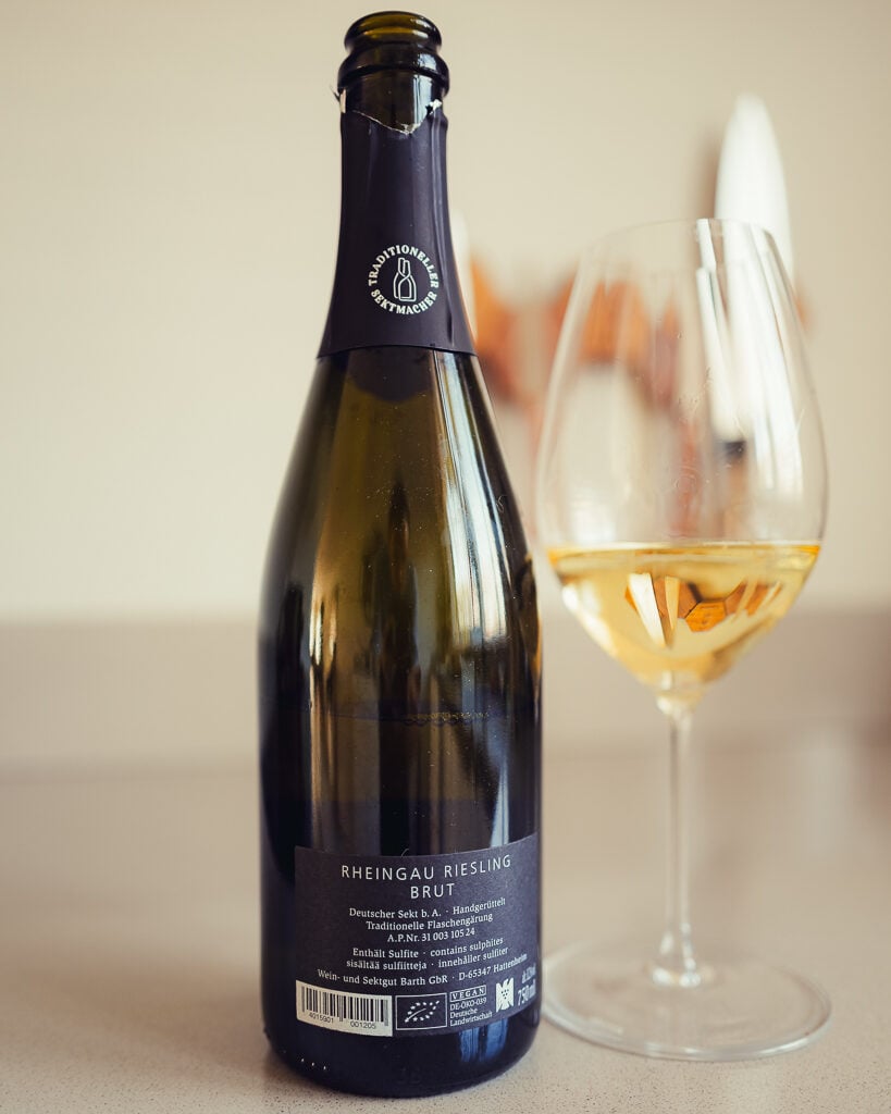 Back label of Barth Rheingau Riesling Brut beside a filled wine glass