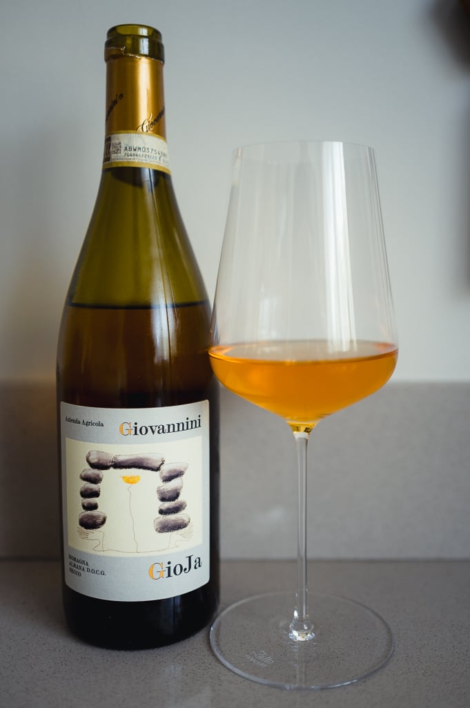 Giovannini Gioja Albana bottle beside a glass of deep amber-orange wine