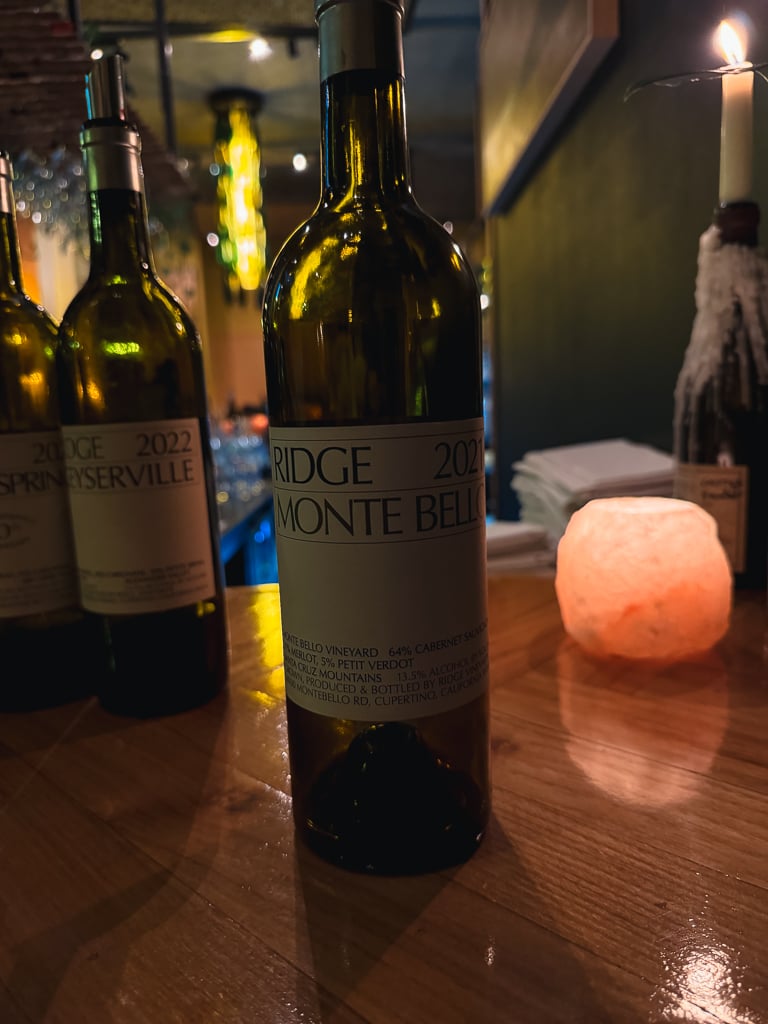 Ridge Monte Bello 2021 bottle on a wooden table by a glowing salt lamp