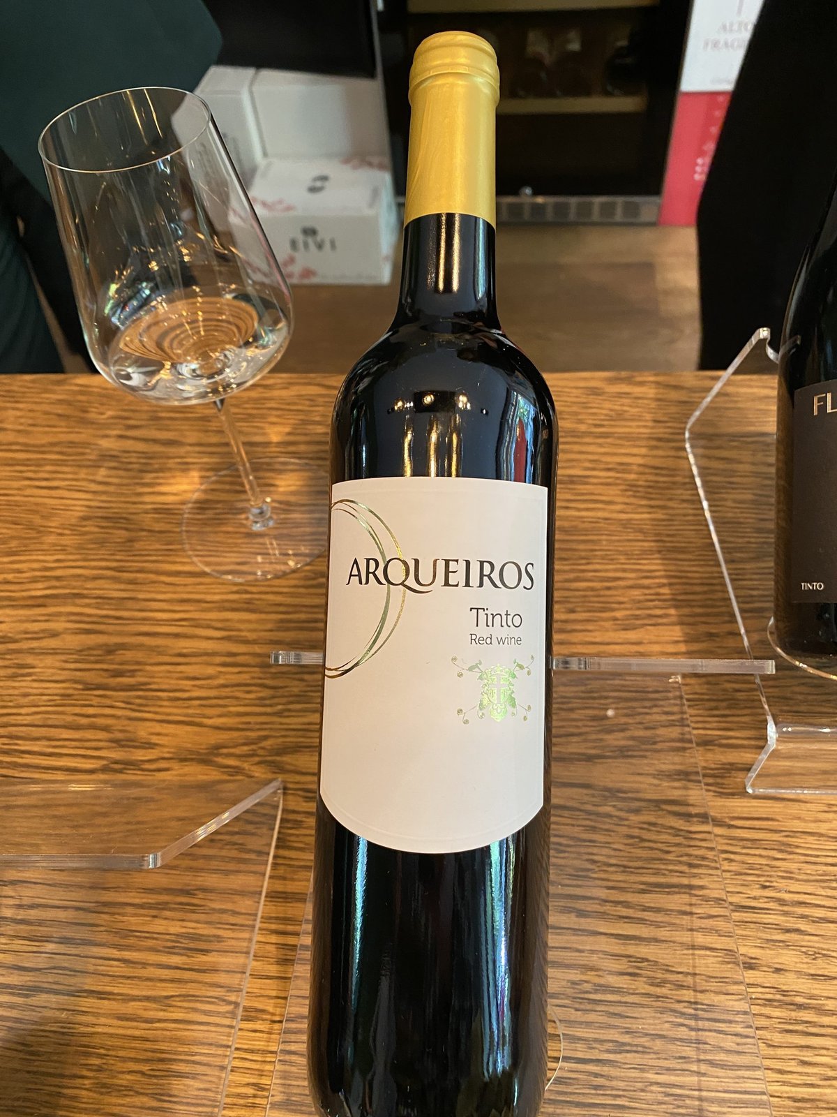 Arqueiros Tinto Portuguese red wine bottle next to an empty glass on a table