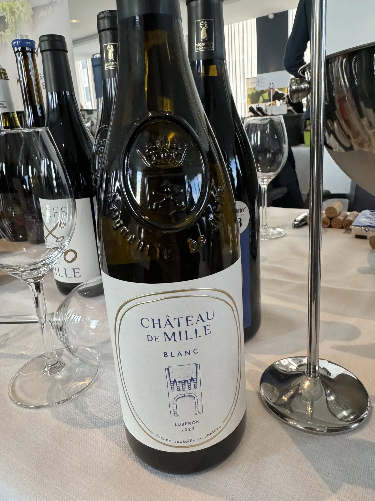 Château de Mille Blanc 2022 bottle with an embossed crown and a white label, on a tasting table