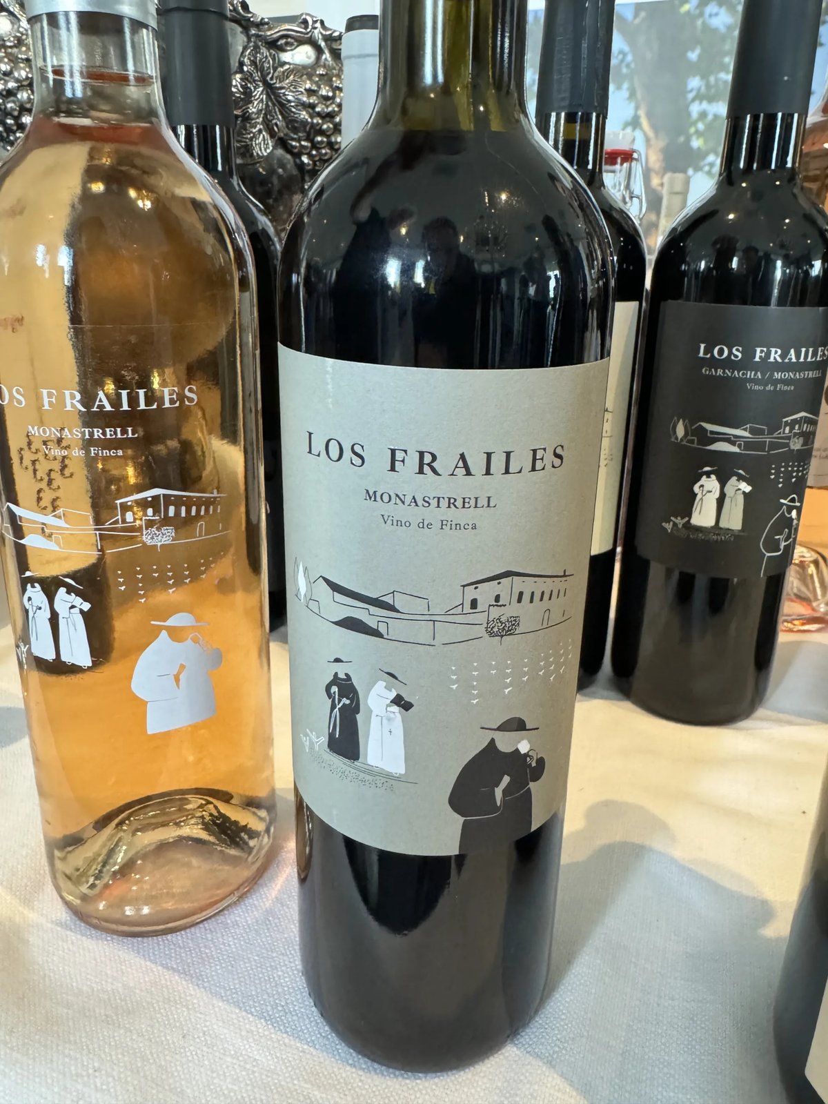 Three Los Frailes Monastrell bottles with monk illustrations, a rosé alongside two reds on a white cloth