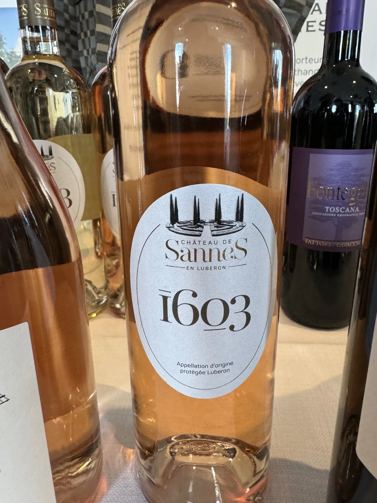 Pale Château de Sannes 1603 rosé bottle with a cypress-tree label, beside a purple-labelled Tuscan red