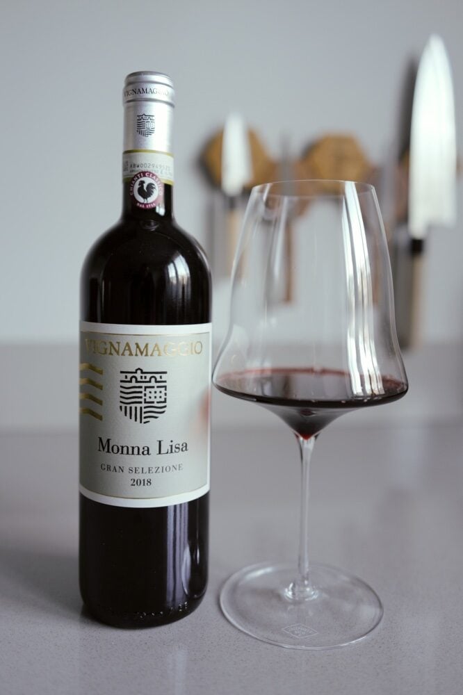 Vignamaggio Monna Lisa Gran Selezione 2018 bottle next to a glass of red wine on a kitchen counter