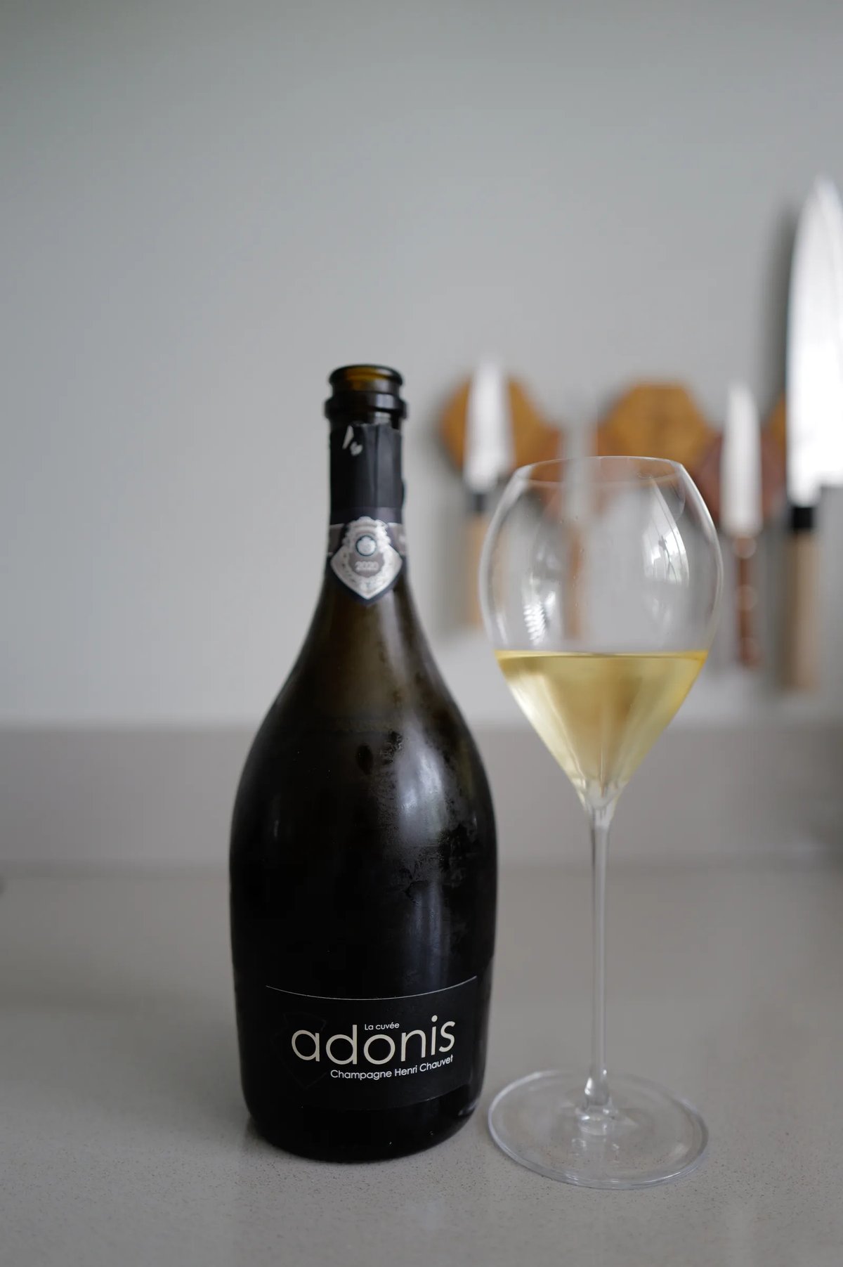 Bottle of Henri Chauvet Adonis 2020 next to a glass of champagne