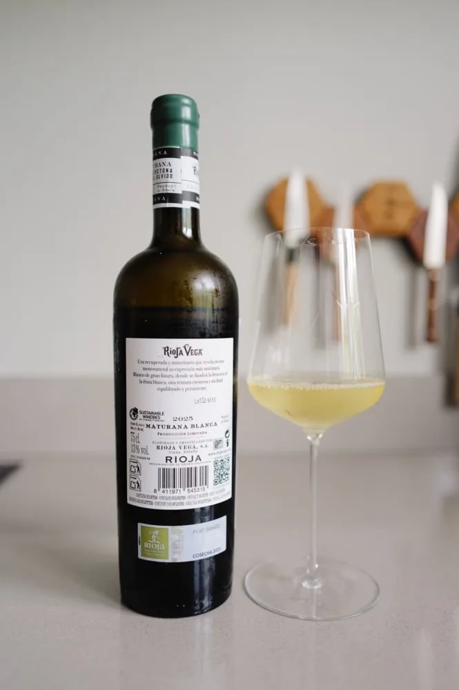 Back label of the Rioja Vega Maturana Blanca 2025 showing the 2025 vintage and the Sustainable Wineries logo, next to a glass of white wine