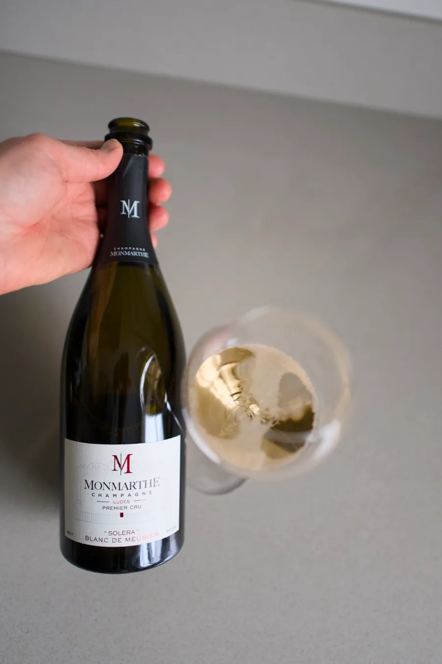 Hand holding a bottle of Champagne Monmarthe Solera Blanc de Meunier
