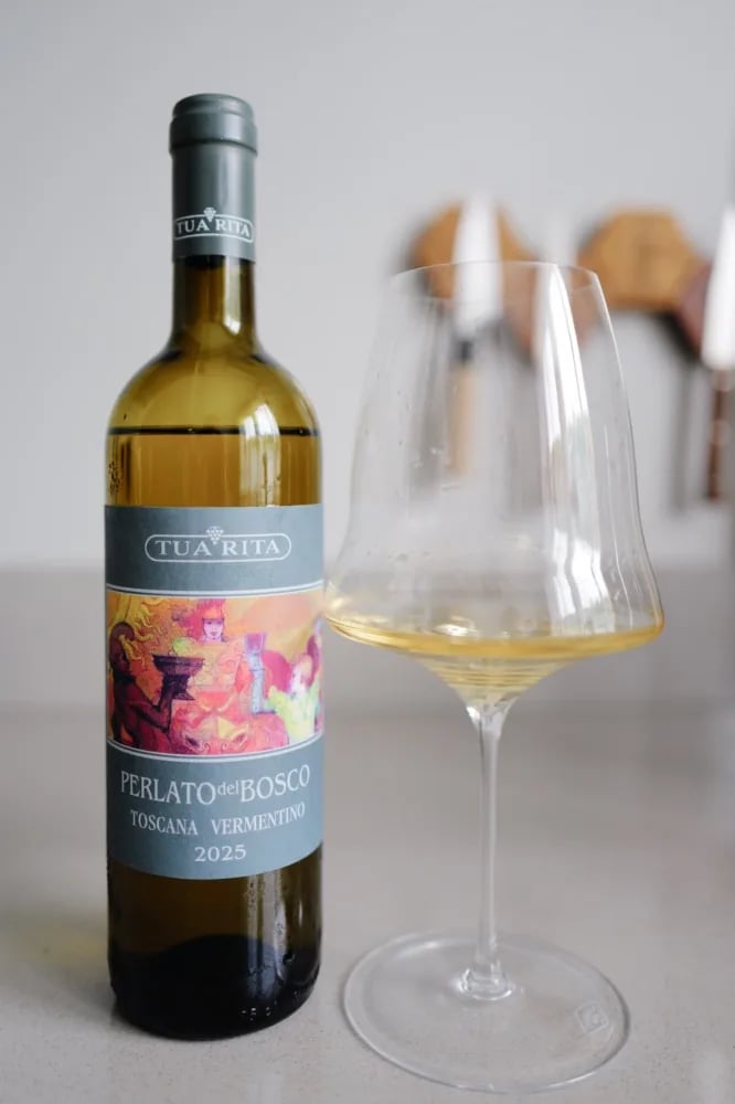 Bottle of Tua Rita Perlato del Bosco Vermentino 2025 next to a filled glass of white wine