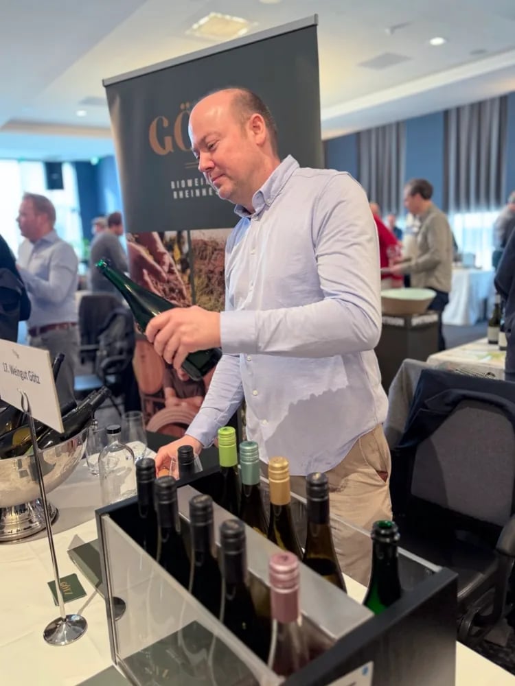 Holger Götz pouring sparkling wine from a side angle