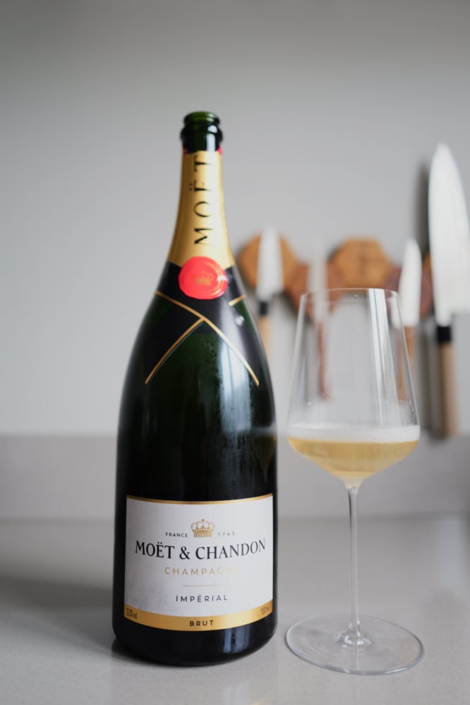 Moët & Chandon Brut Impérial next to a wine glass with golden champagne and a fine mousse