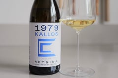 Bottle of 1979 Kalos Stergianos 2022 Greek retsina with mountain forest in the background