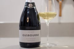 Gusbourne Blanc de Blancs bottle next to glass with English vineyard