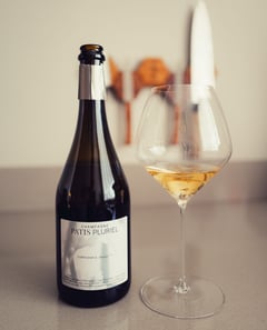 Bottle of Les Sèves champagne by Patis Pluriel next to a filled glass