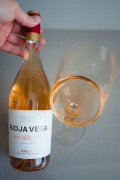 Bottle of Rioja Vega 1882 Rosado next to a glass of salmon-coloured Spanish rosé