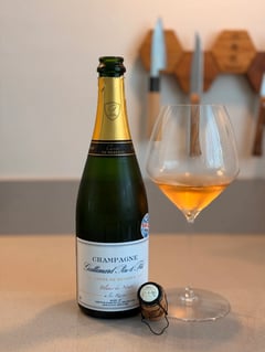 Bottle of Champagne Gallimard Cuvée de Réserve Blanc de Noirs next to a glass of copper-coloured champagne