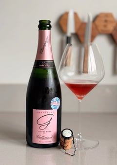 Bottle of Gallimard Cuvée Rosé Brut de macération beside a glass of deep raspberry-red champagne