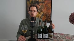 Jeroen Vonk at the table holding a glass of champagne, with three bottles of B. Girardin lined up during the lees aging blind tasting