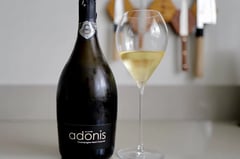 Bottle of Henri Chauvet Adonis 2020 Blanc de Blancs standing next to a full glass on a kitchen counter
