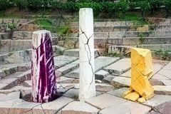 Brutalist illustration of three fractured columns in the colors of Italy, France and Spain above a vineyard grid