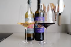 Tua Rita Perlato del Bosco Vermentino 2025 and Lodano 2024 side by side on a kitchen counter, with a glass of white and a glass of red