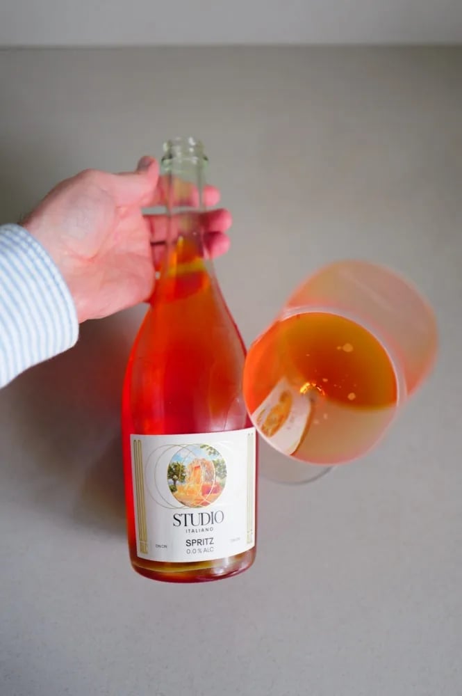 Kolonne Null Spritz Studio Italiano being poured, with a slice of orange in the glass