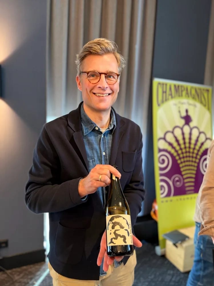 Mark Haasdijk van Champagnist met Field Blends-fles voor de gele en paarse Champagnist-banner