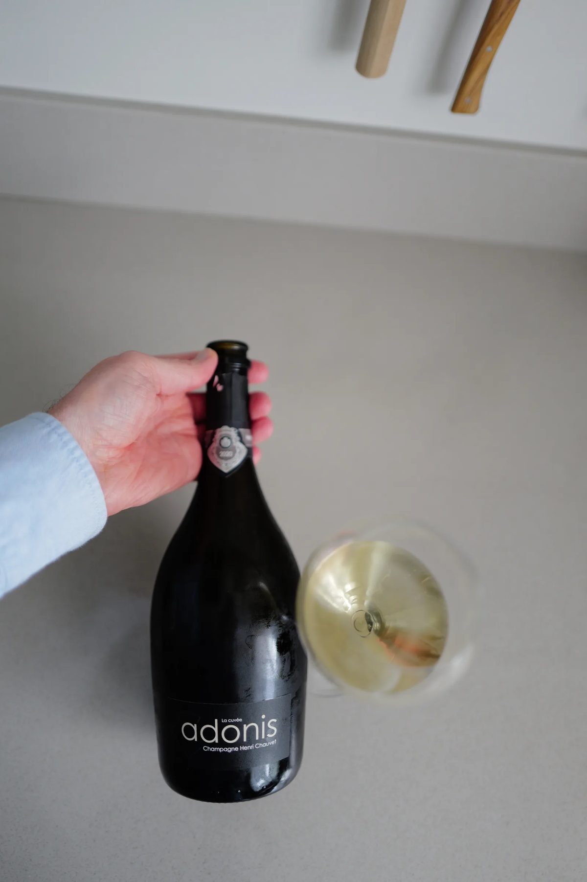 Fles Henri Chauvet Adonis 2020 met het front-label, naast een glas champagne